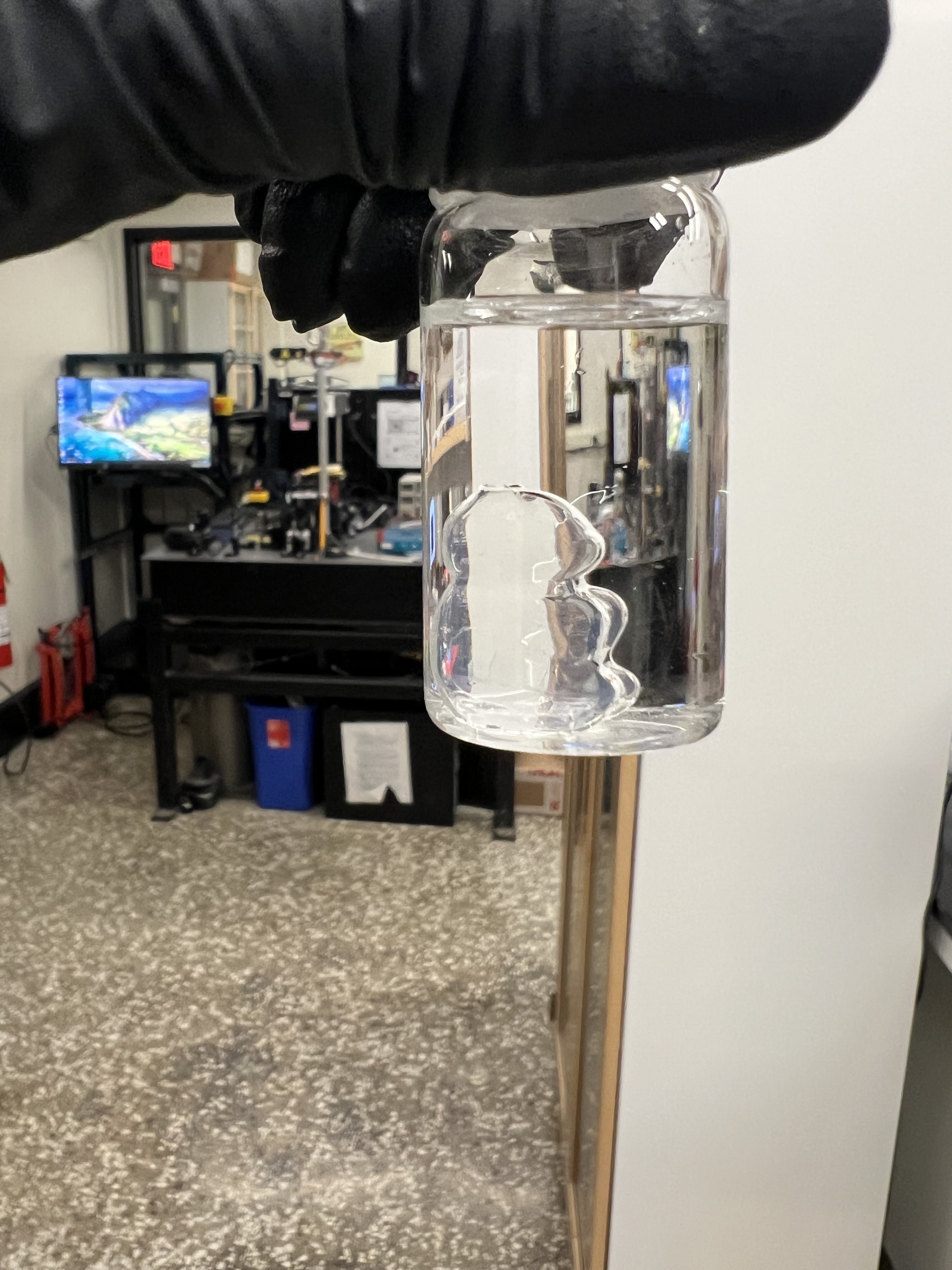 Side view of a transparent gummy-bear-shaped print held in a glass container.